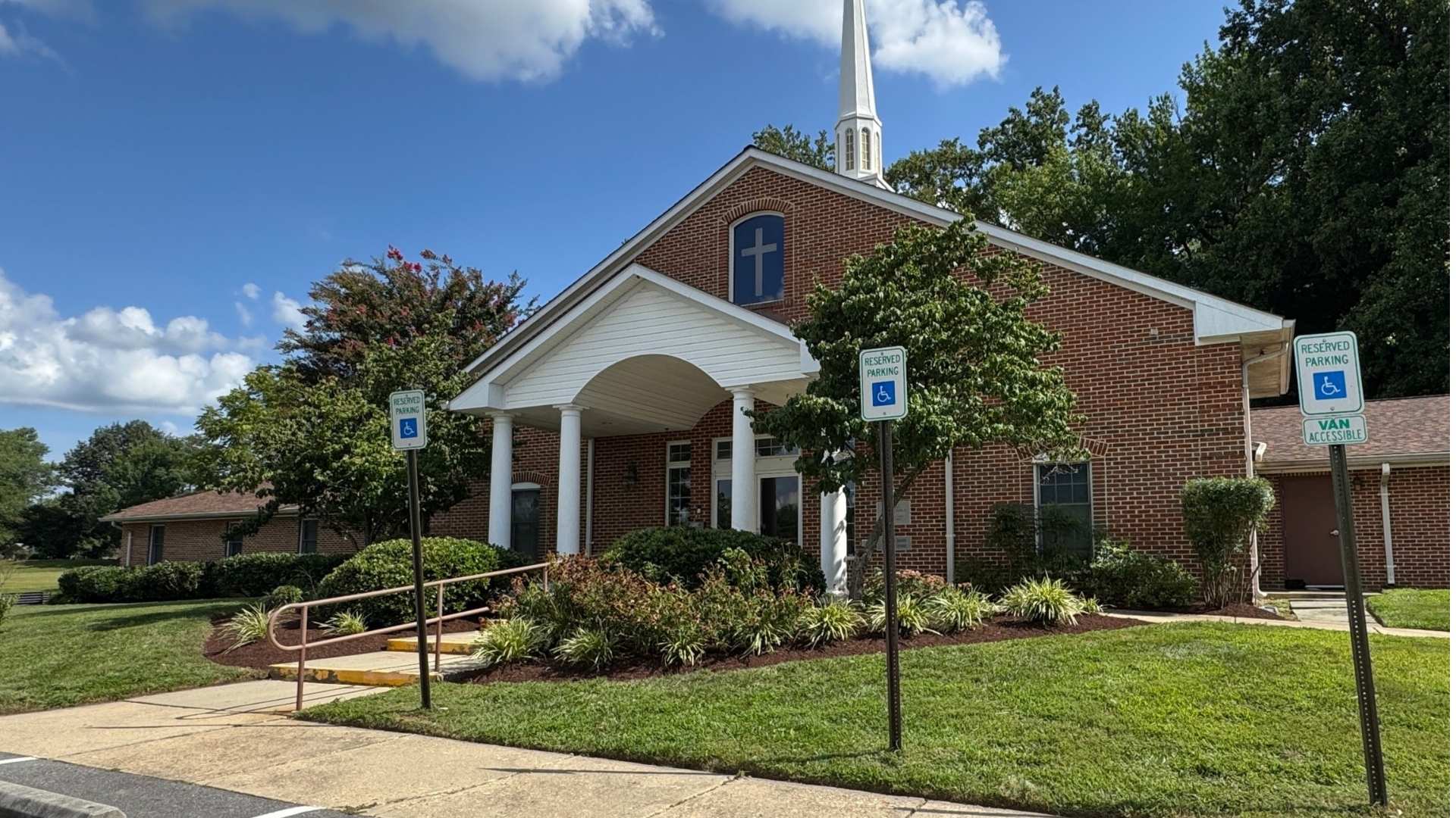 Small brick church with a steeple on a sunny day