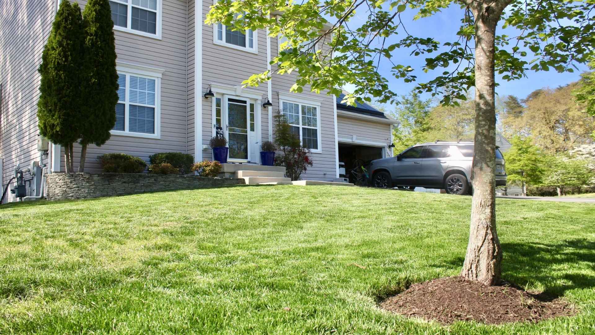 House with a well-maintained lawn and a car parked in the driveway.