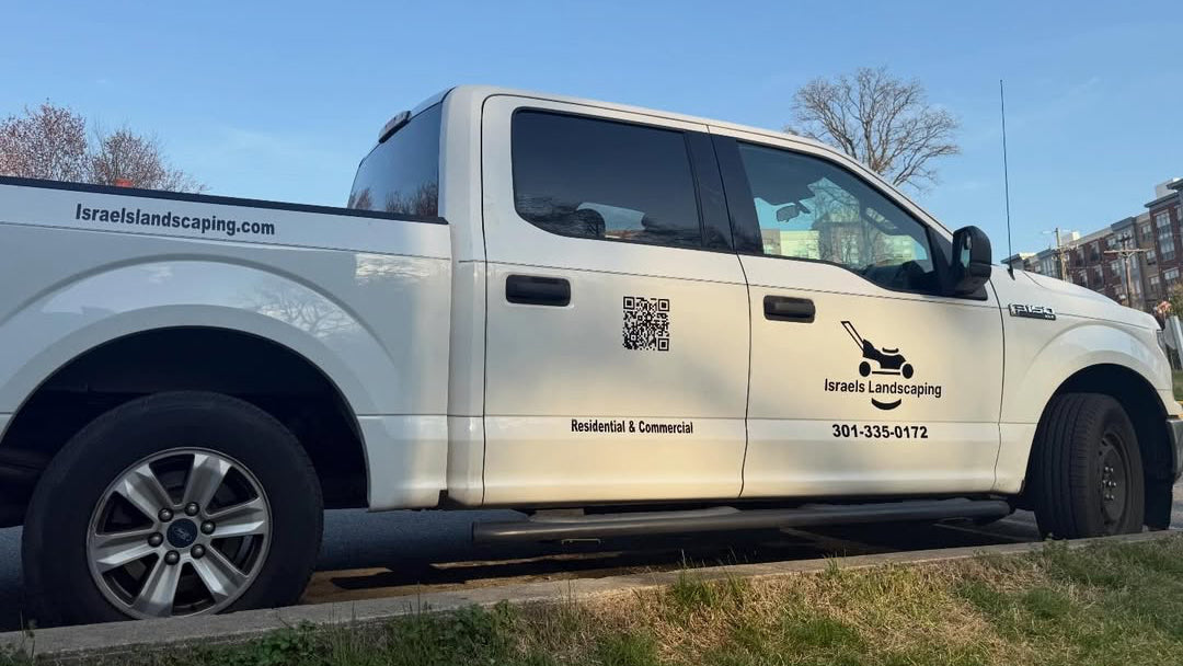 White Ford F-150 service truck with Israels Landscaping branding, logo, and contact information parked on a street.